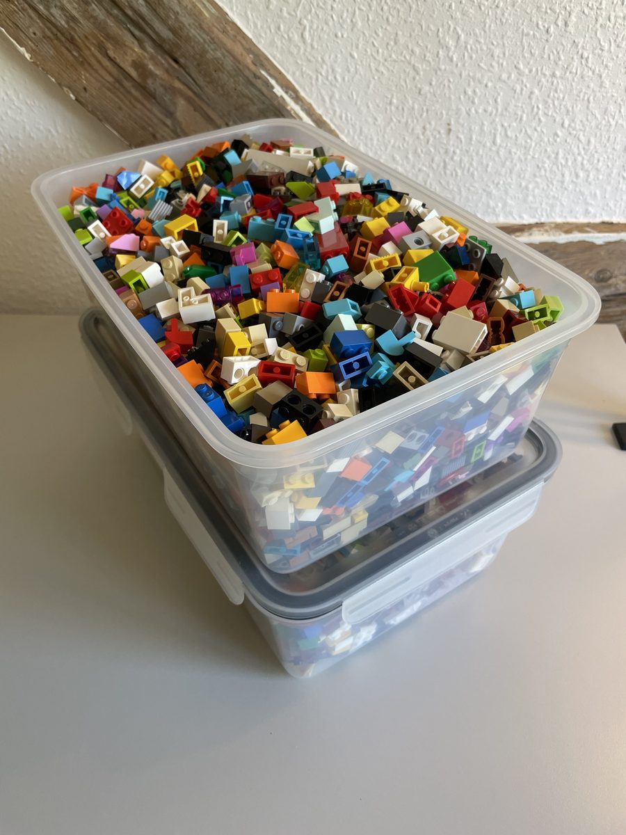 A clear plastic tub filled with thousands of loose LEGO parts