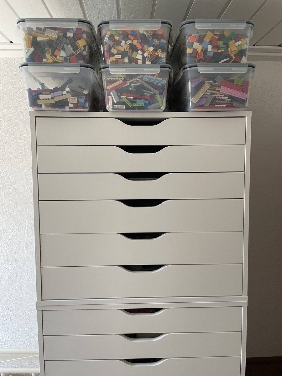 A tall white drawer cabinet with tubs of loose parts stacked on top